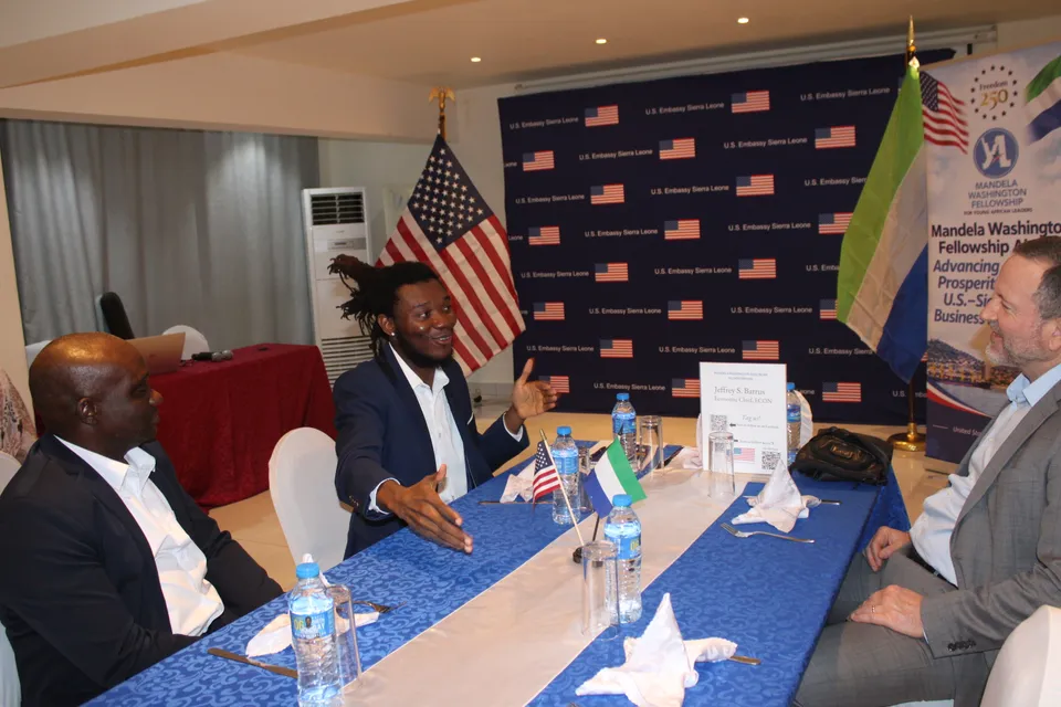 Joseph Jawah Kebbie gestures while contributing to a discussion around the business dinner table.
