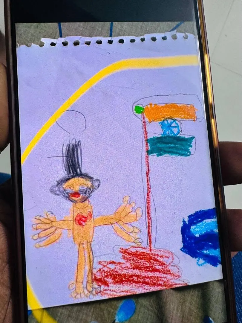 A child’s drawing of Joseph with tall hair, outstretched arms and a red heart, beside the Indian flag, shown on a phone screen.